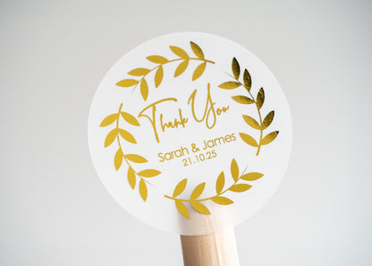 Thank you sticker with a round leaf border. The name of the couple sits underneath &quot;thank you&quot; written in a handwritten font. The design is finished with metallic foil for a lovely shine.