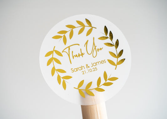 Thank you sticker with a round leaf border. The name of the couple sits underneath &quot;thank you&quot; written in a handwritten font. The design is finished with metallic foil for a lovely shine.