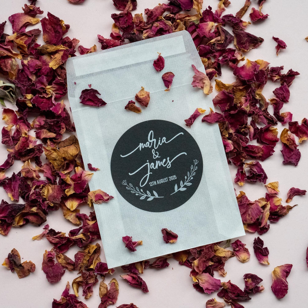 A black sticker with the names of the married couple in a lovely handwritten font in the middle of the sticker. A leaf frame is at the bottom with the date of the wedding day. Printed in white ink so it stands out on the black sticker.