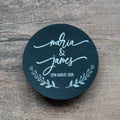 Round black sticker with 'Maria & James' and date printed using white ink